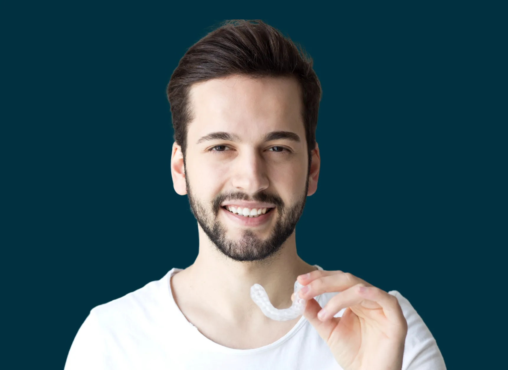 man smiling holding an invisable aligner