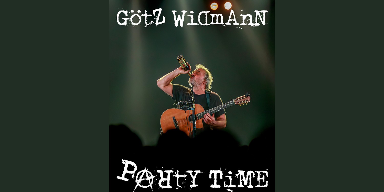 Götz Widmann auf der Bühne mit seiner Gitarre und aus einer Bierflasche trinkend.