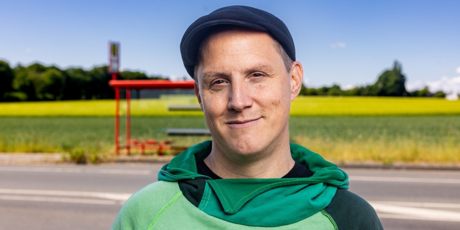 Sebastian 23 steht vor einer Bushaltestelle.