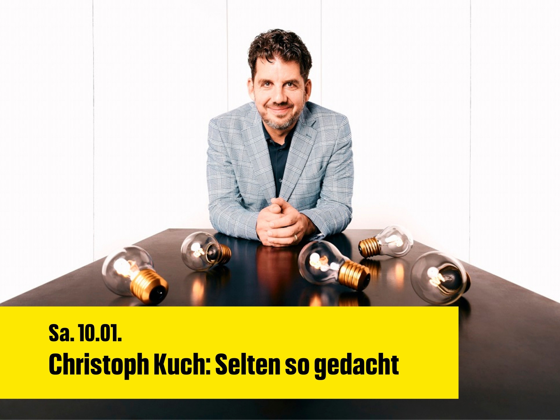 Christoph Kuch sitzt am Tisch. Vor ihm liegen Glühbirnen, die leuchten.