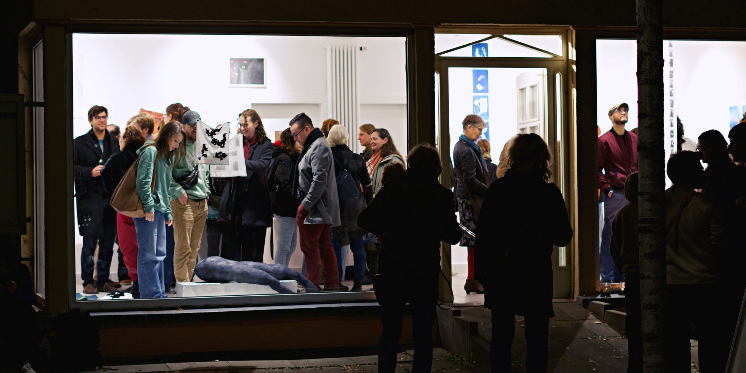 Menschen bei einer Ausstellung mit verschiedenen Kunstobjekten.
