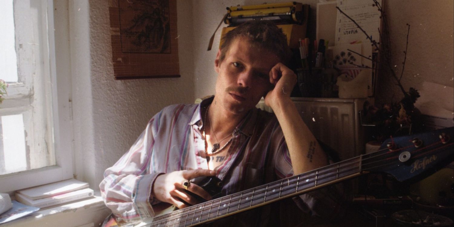 Jesper Munk sitzend mit Gitarre.