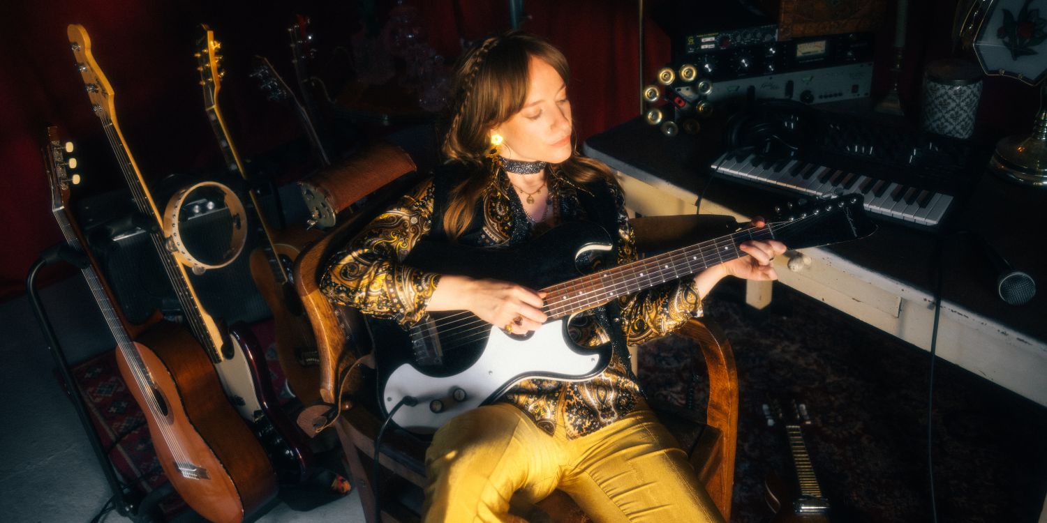Lùisa im Studio sitzend mit Gitarre in der Hand.