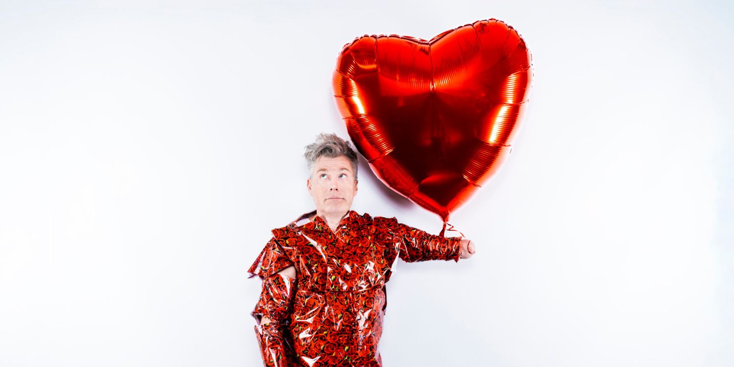 Martin Fromme mit rotem Glitzerpapier umhüllt und rotem Herzluftballon an seinem Arm.
