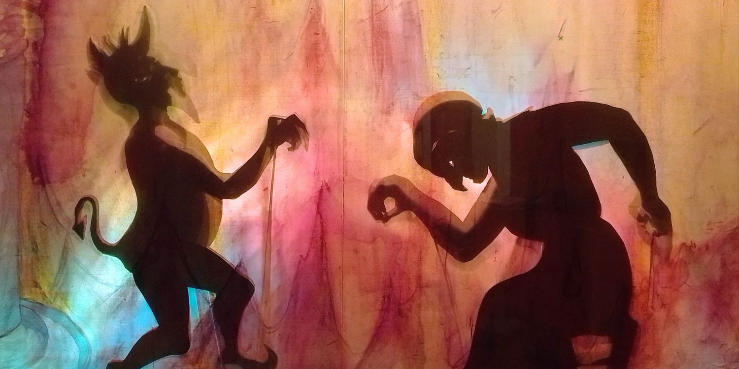Szene aus dem Stück: Man sieht eine farbige Leinwand und den Schatten von einem Teufel