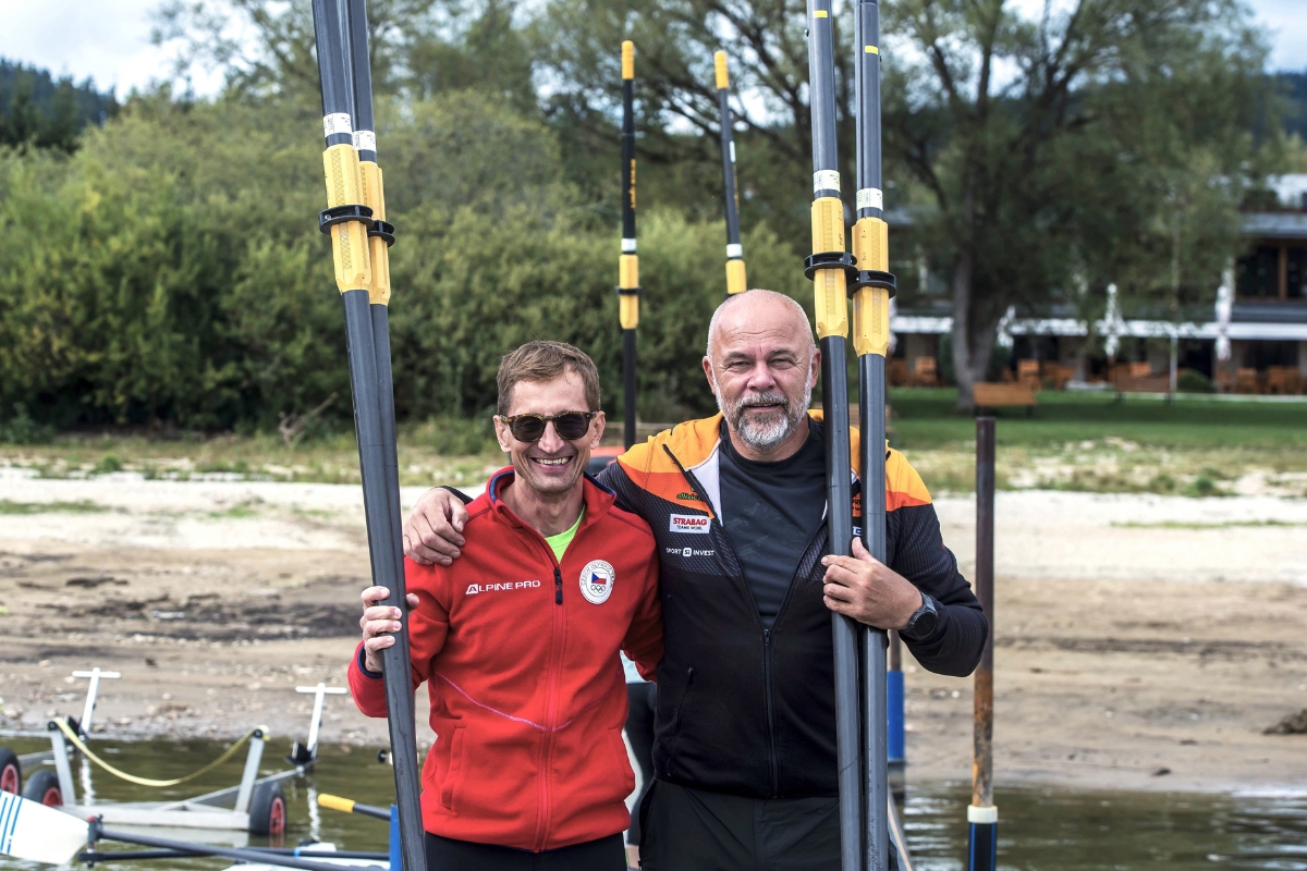 Two colleagues holding oars on the shore of Lipno