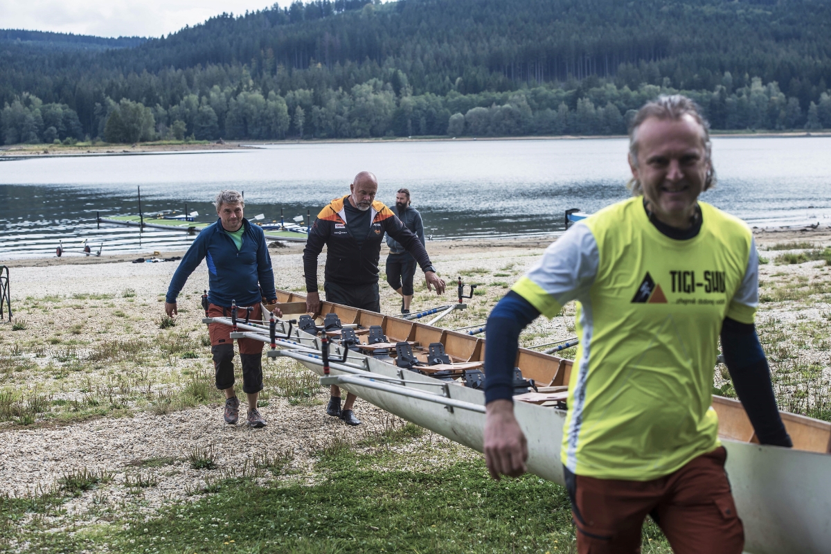 Colleagues carrying a rowing boat to the water at Lipno