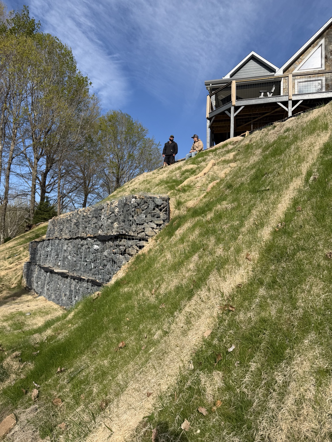 After: the gabion wall below the home, with vegetation establishing across the restored slope.