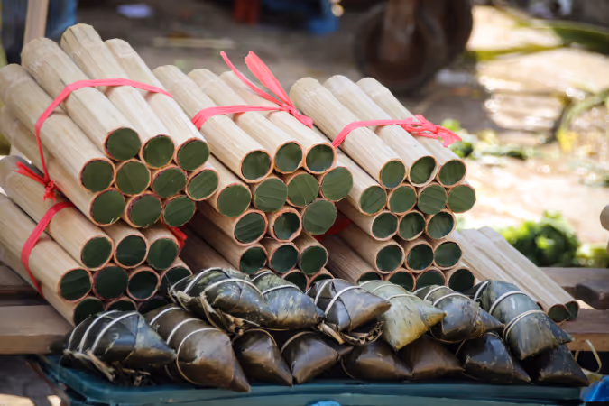 Bundles of Cơm Lam (sticky rice in bamboo tubes) and traditional leaf-wrapped rice cakes at a local market in Sapa.