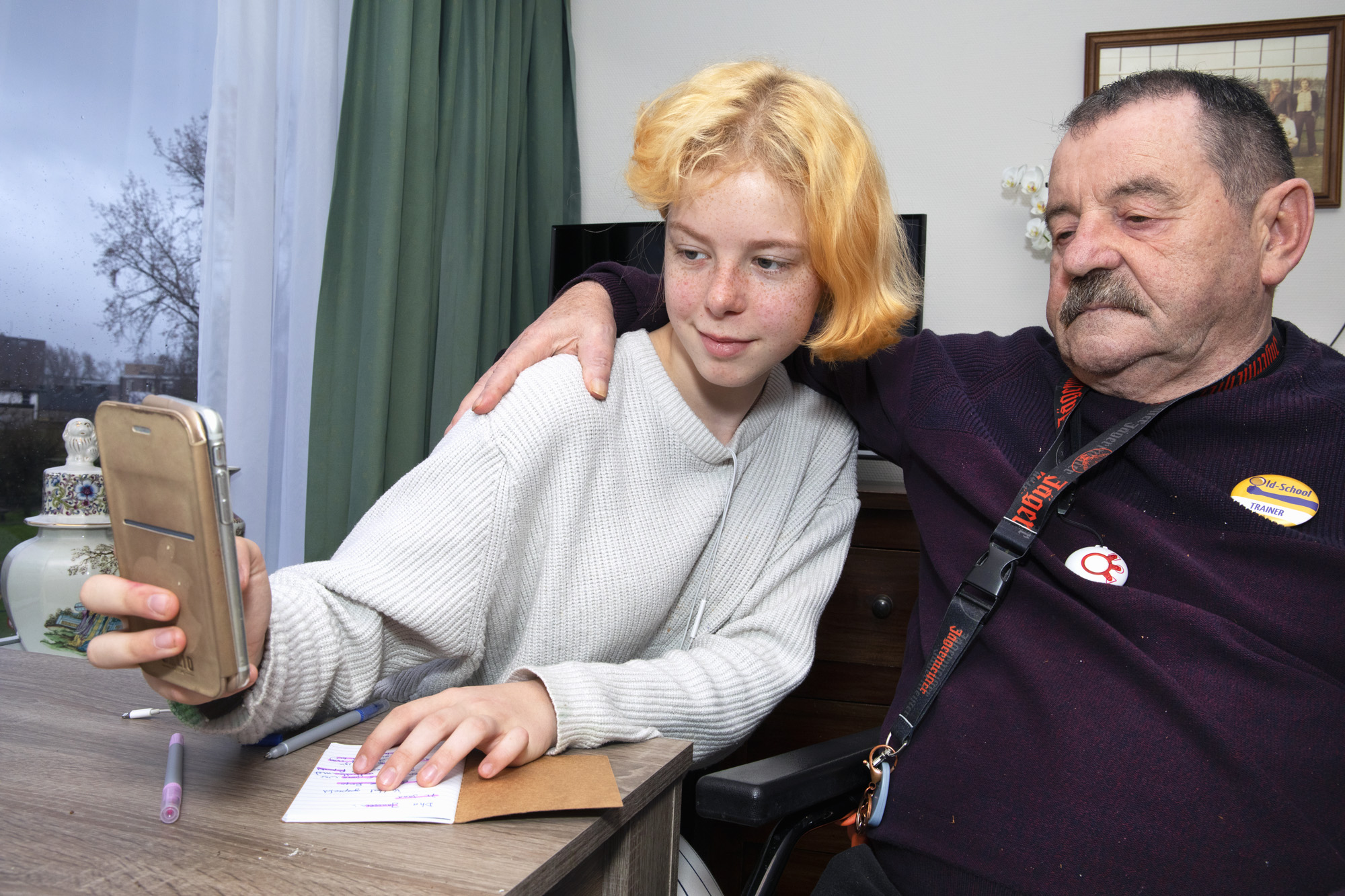 Foto van een MDT deelnemer die een selfie neemt van zichzelf en een oudere man, met wie ze mogelijk werkt in het MDT project
