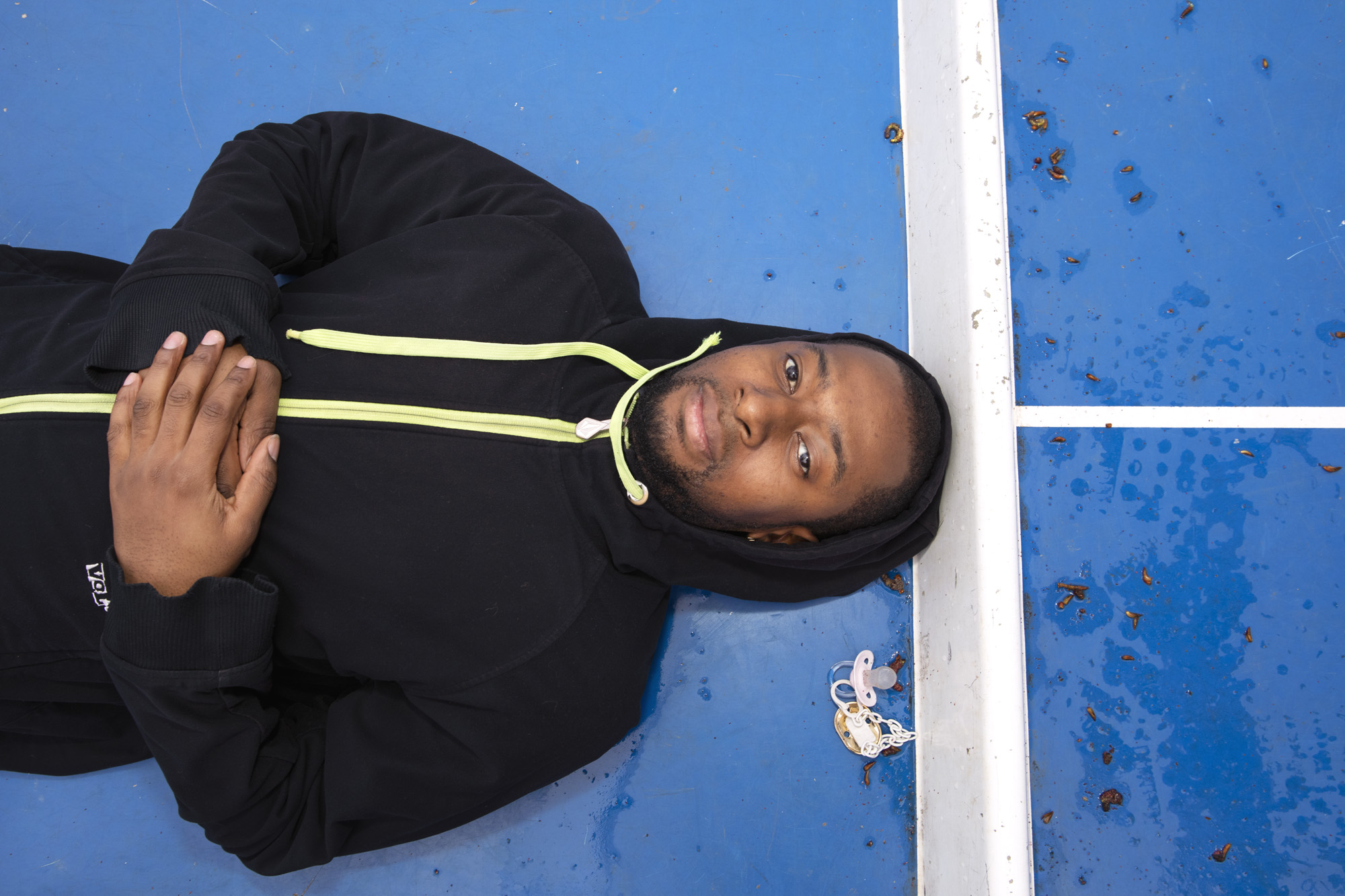 Portret van een jonge MDT deelnemer, liggend op de grond van iets dat lijkt op een tennisbaan