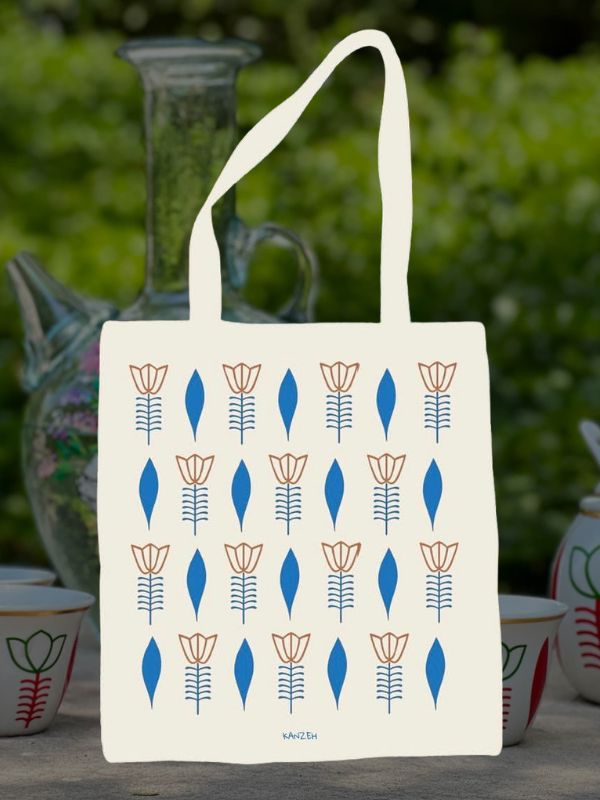 White tote bag with a repeating pattern of brown flowers and blue leaves arranged in rows.
