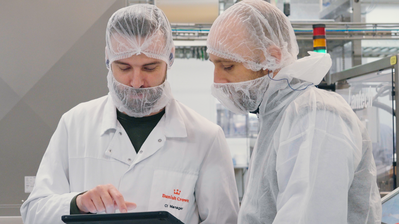 Two employees in a factory looking at a tablet