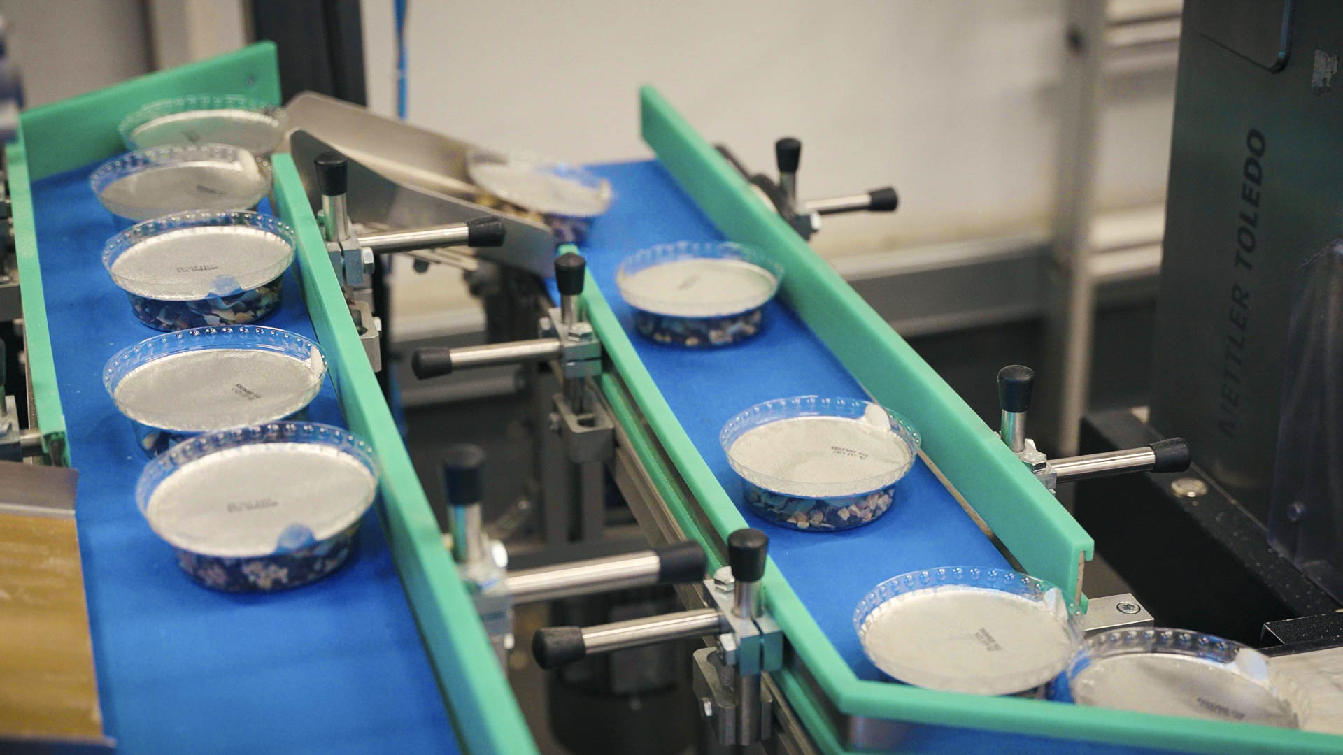 Small round containers on a conveyor belt in a factory.
