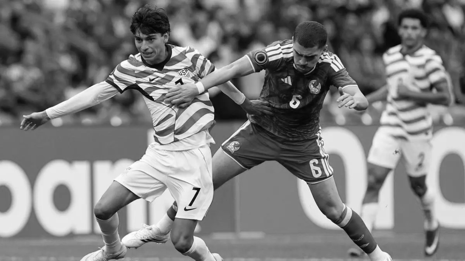 Two soccer players from opposing teams competing for the ball during a match.