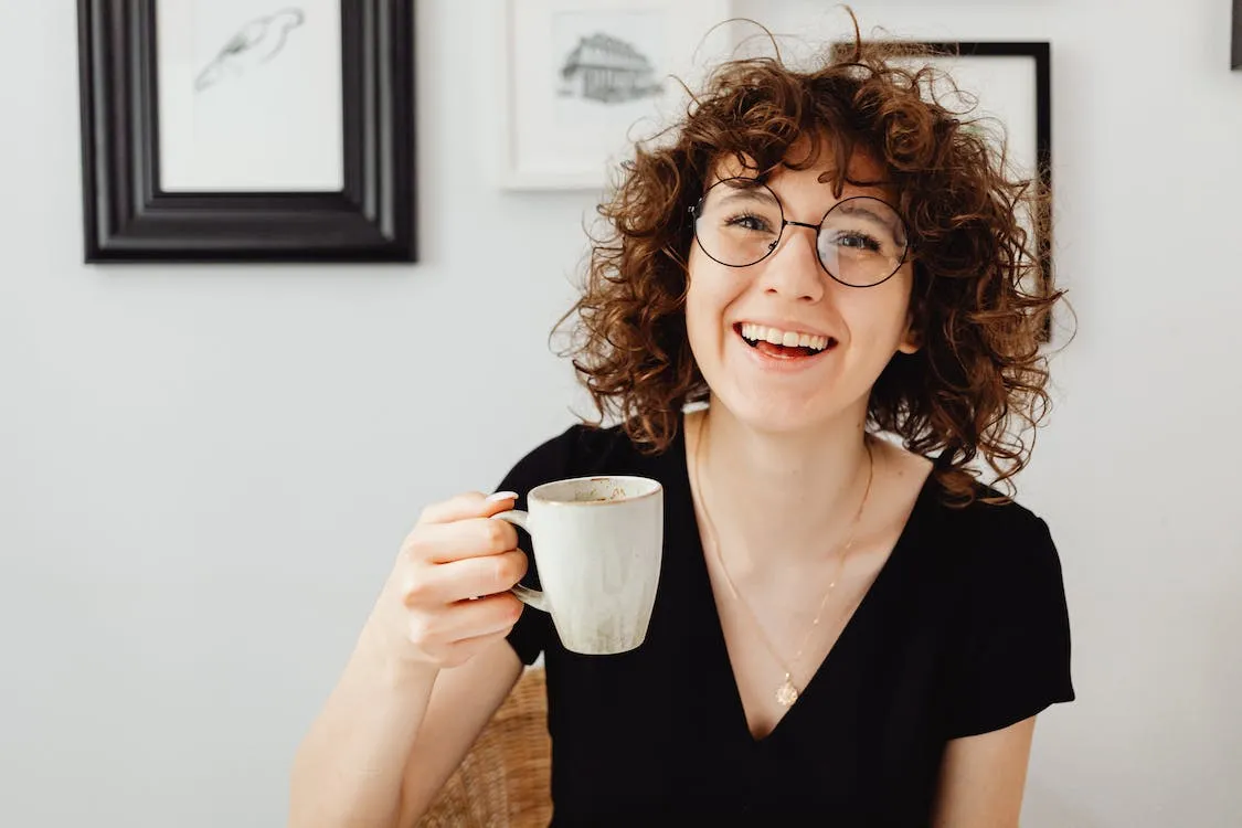 La misma mujer levantando la taza y feliz.