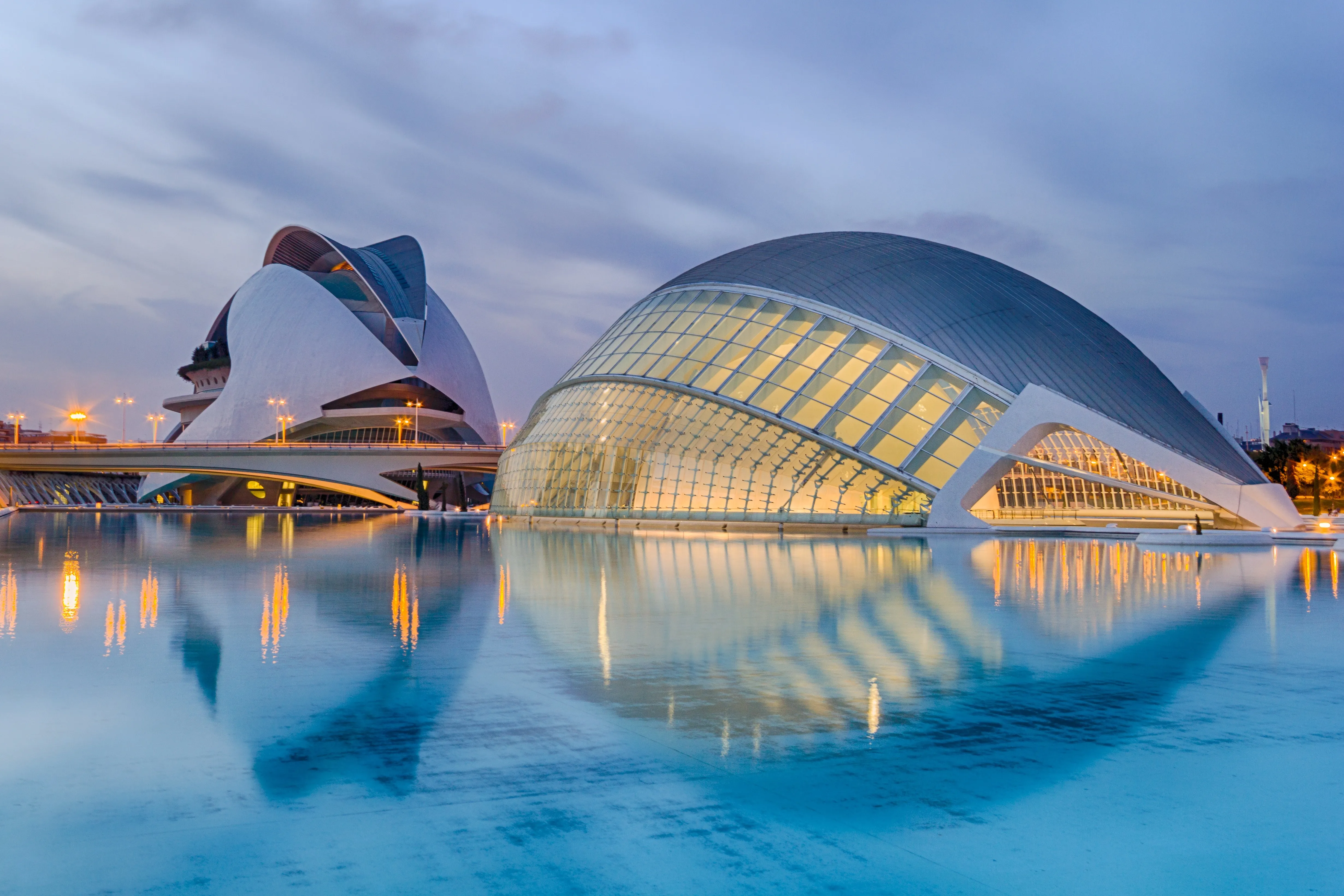 Vista de la Ciudad de las Artes y las Ciencias en Valencia con sus edificios modernos iluminados y reflejados en el agua al revés, ilustrando el mercado de mudanzas locales