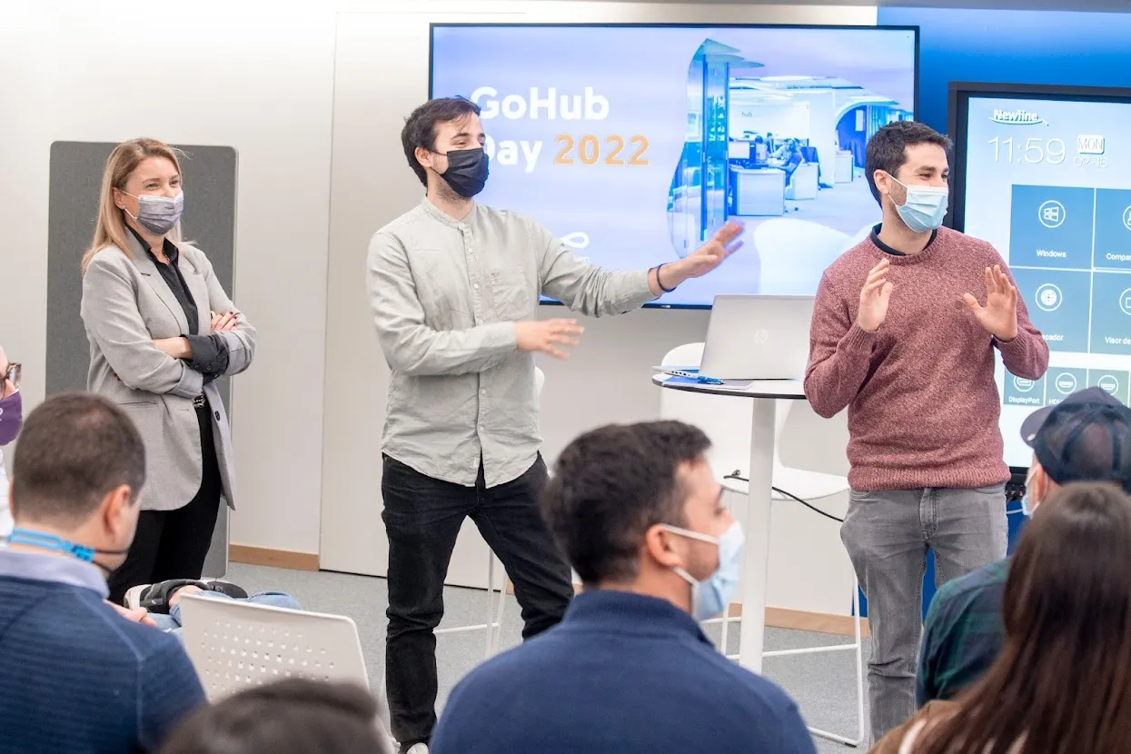 Varios profesionales con mascarilla realizan una presentación corporativa frente a una pantalla con el texto GoHub Day 2022, ilustrando la participación de Okify en el ecosistema emprendedor