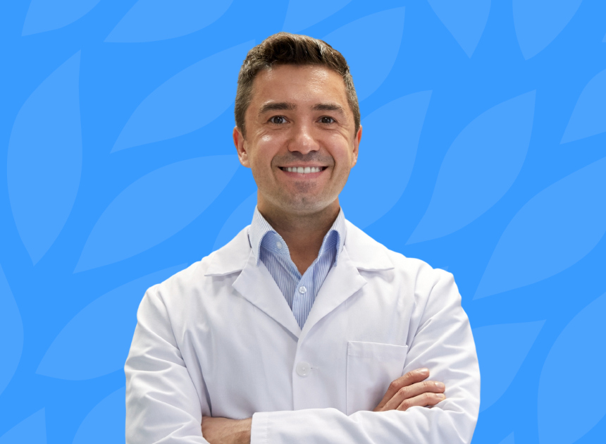A dentist smiling with his arms folded. On a blue background.