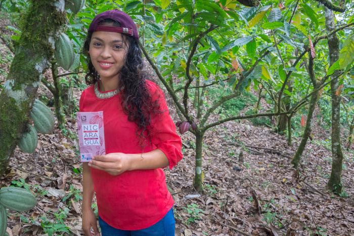 Young cocoa farmer holding chocolate bar