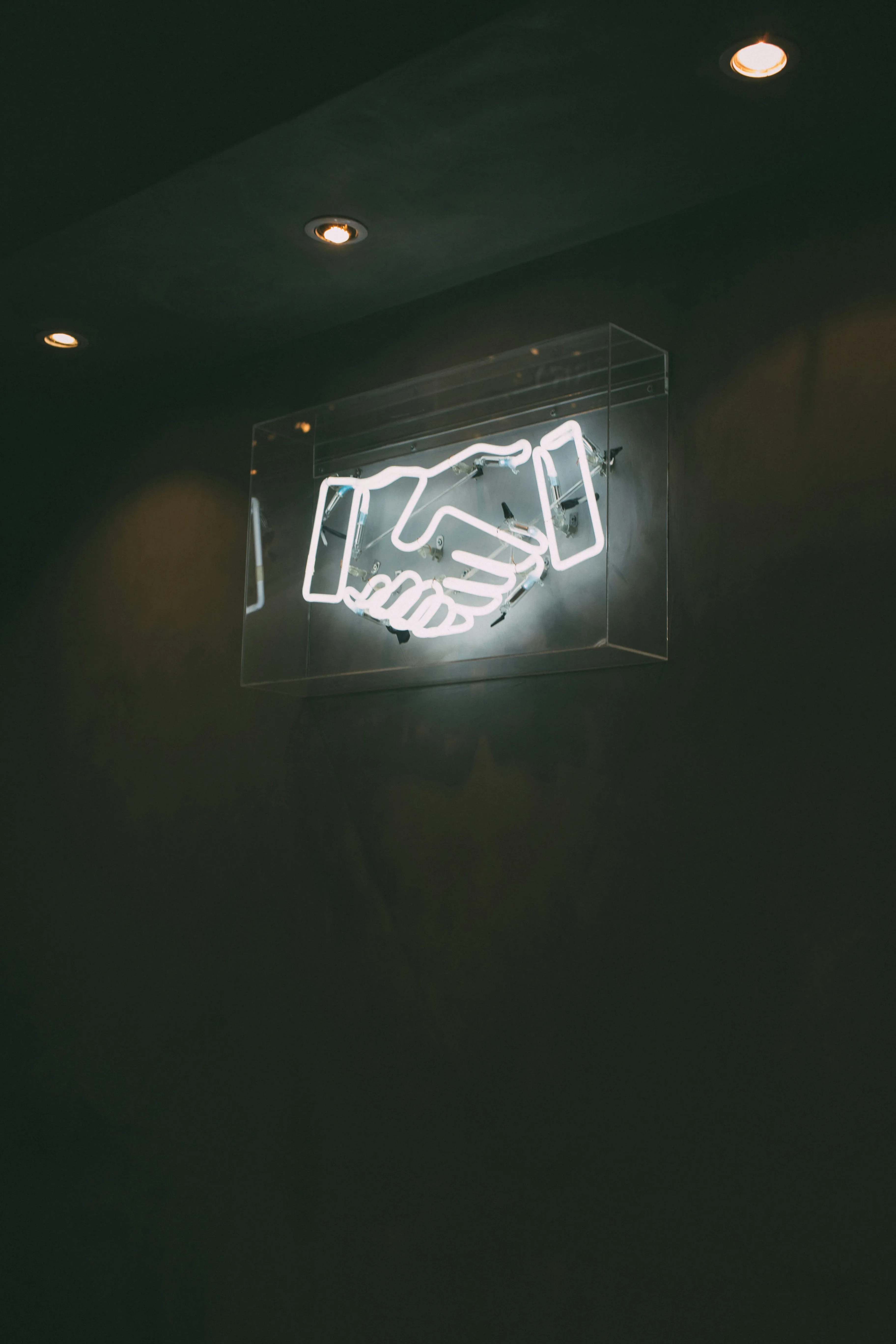 A neon sign of a handshake representing the human side of construction and subcontractor management.