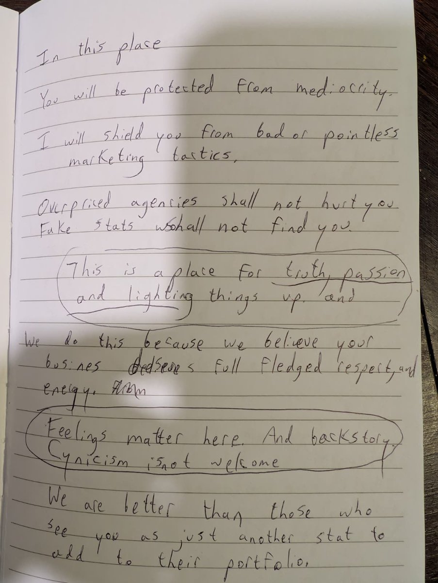 Handwritten notebook page drafting a brand manifesto that begins: In this place, you will be protected from mediocrity. Two lines are circled.