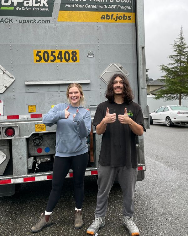 College student and Thumbs Up Moving Labor mover standing in front of UPack truck after successful dorm move.