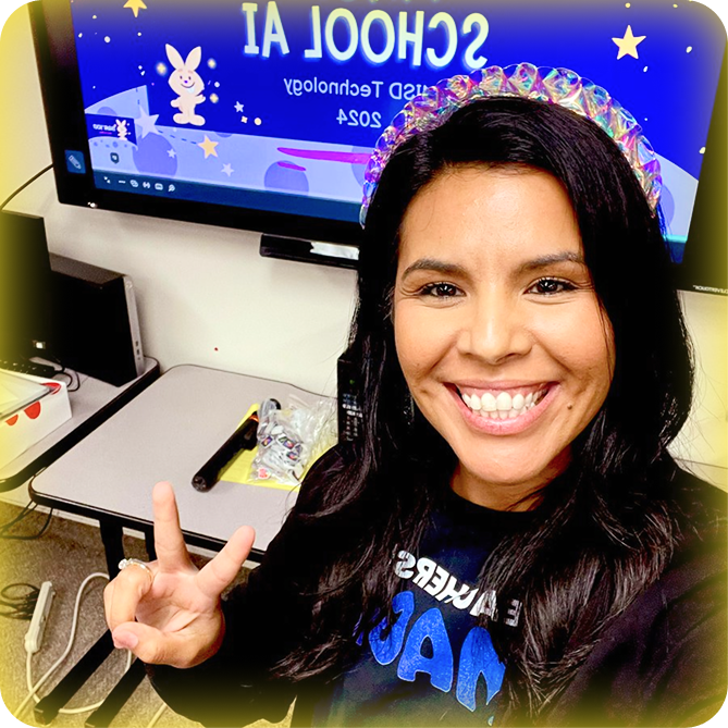 Image of a smiling female teacher with brown hair giving the peace sign and wearing a Black Teachers are Magic T-shirt and standing in front of a computer monitor with a MagicSchool presentation on the screen.