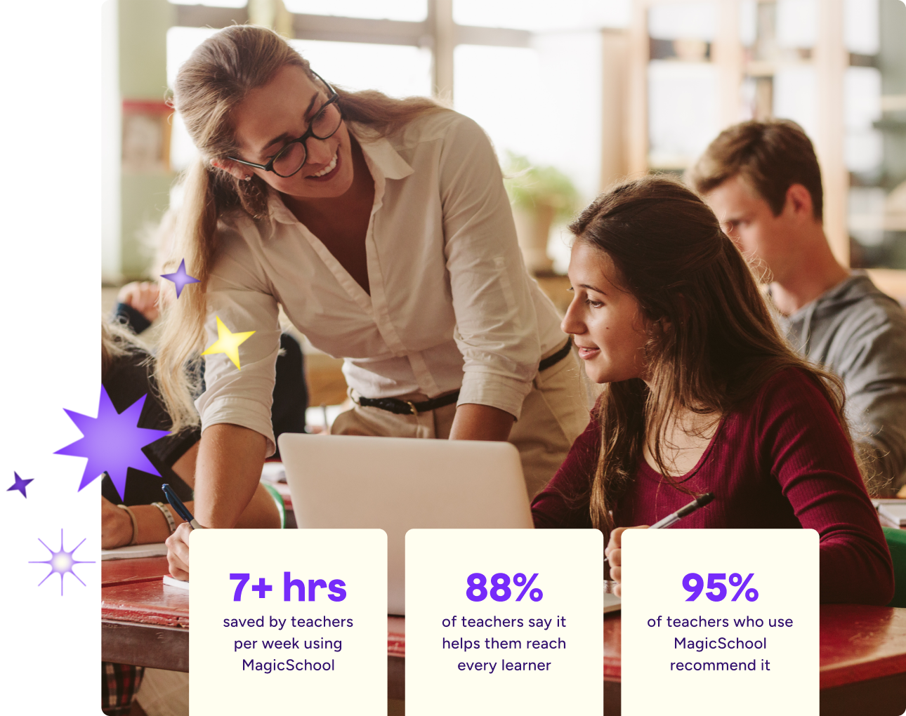 A teacher leans over a student’s desk, smiling as they look at a laptop together in a classroom. Other students work in the background