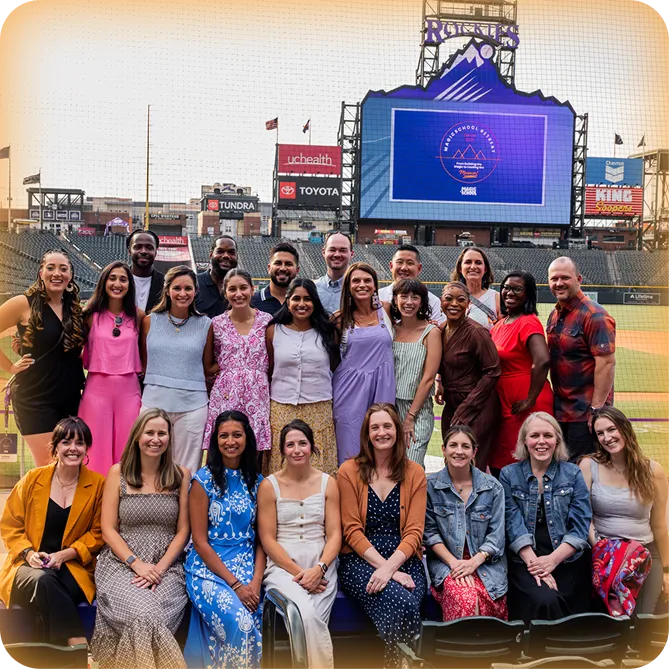 A large group of MagicSchool employees posing inside of the Colorado Rockies stadium at a company offsite event.