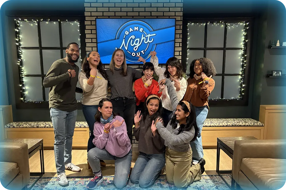 A group of new MagicSchool employees posing in front of a 'Game Night Out' sign during a team building event.