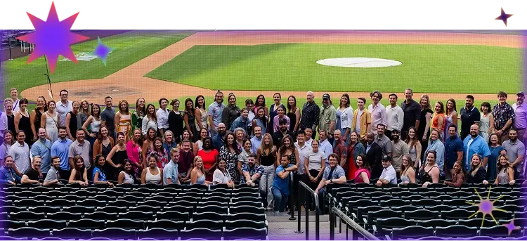 A photo from July 2025 of the full MagicSchool team posing for a company photo in front of the Colorado Rockies field during a company retreat.
