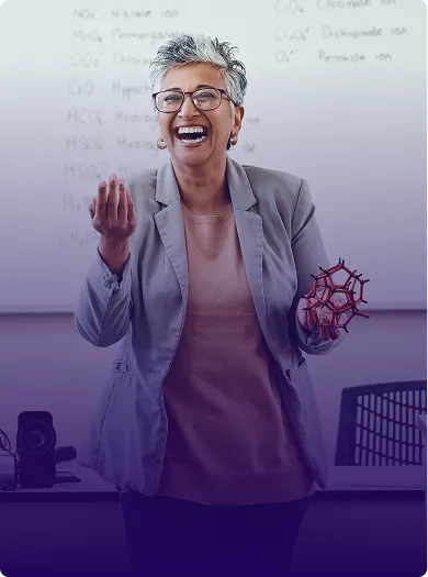 Image of an educator smiling and standing in front of a classroom.