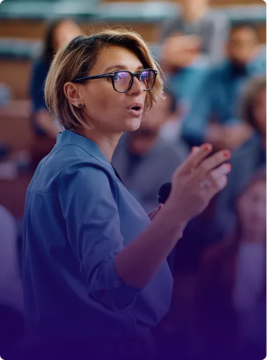 Image of an administrator speaking to a large group in an auditorium setting.