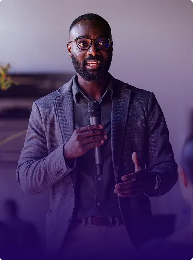 Image of an administrator holding a microphone and speaking to an audience.