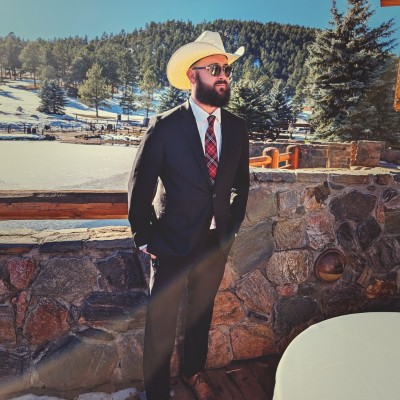 Photo of Keanon O'Keefe in a suit jacket and cowboy hat looking into the distance