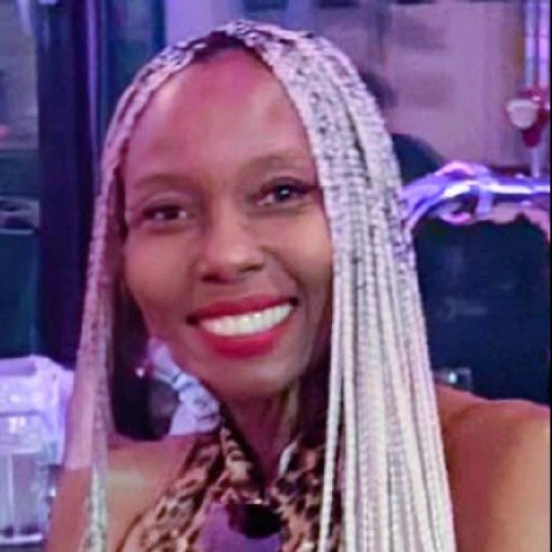 Headshot of Fiona Wright, smiling with long light-colored braided hair, wearing a sleeveless patterned top.