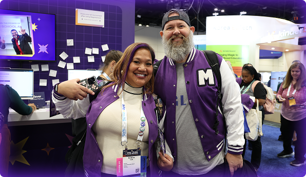 Two educators wearing purple, MagicSchool branded Letterman's jackets in front of the MagicSchool trade show booth.