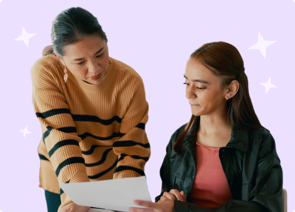 Image of a teacher reviewing a printed assignment with a student sitting at a desk.