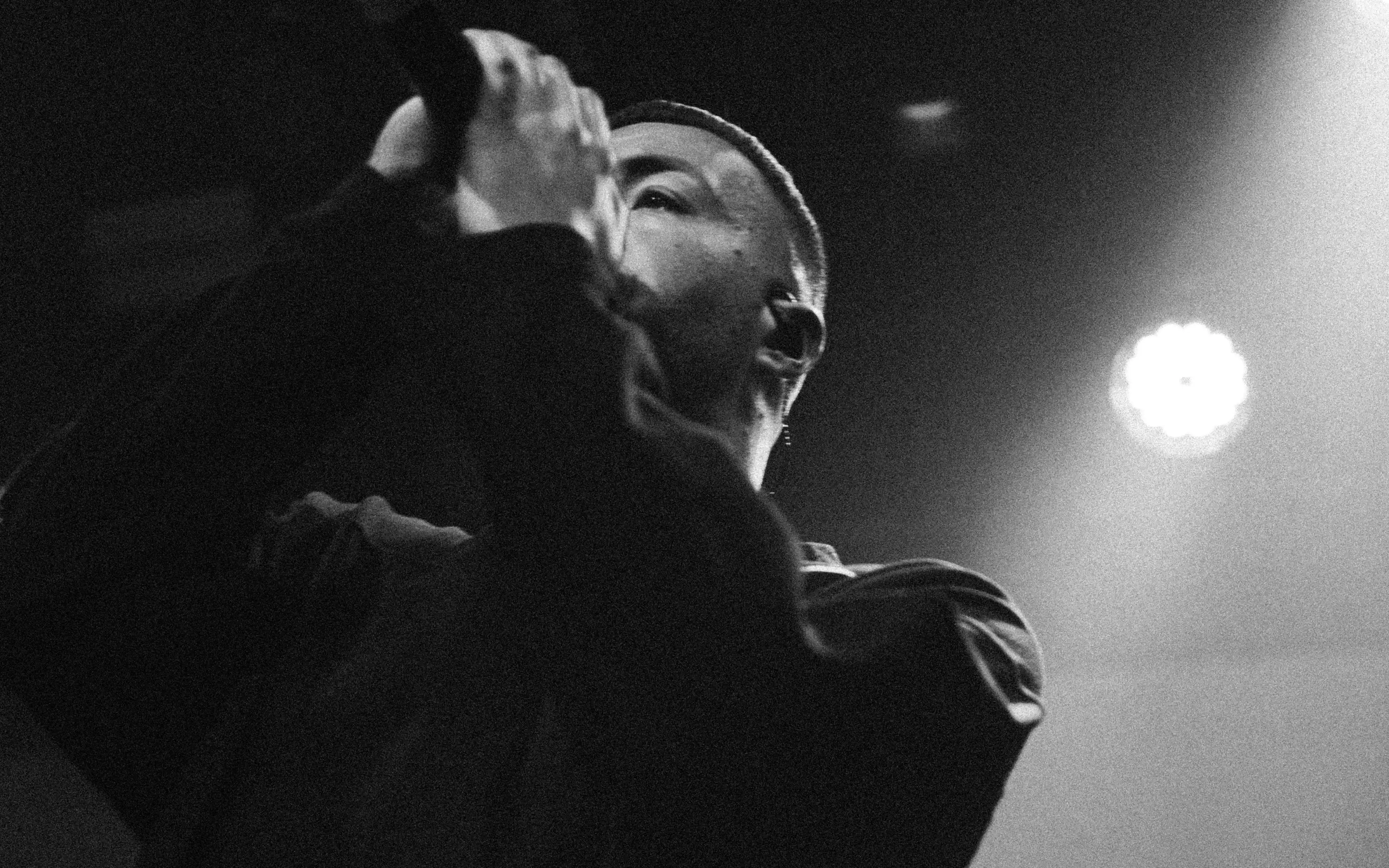 Civo singt im Profil ins Mikrofon, beleuchtet von einem Scheinwerfer beim Konzert in Köln.