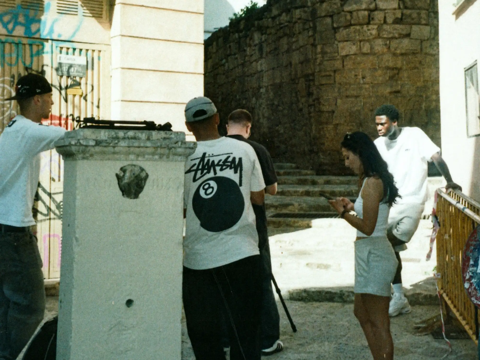 Das Shootingteam geht gemeinsam durch eine Straße in Palma, vorbei an Palmen und historischen Mauern.