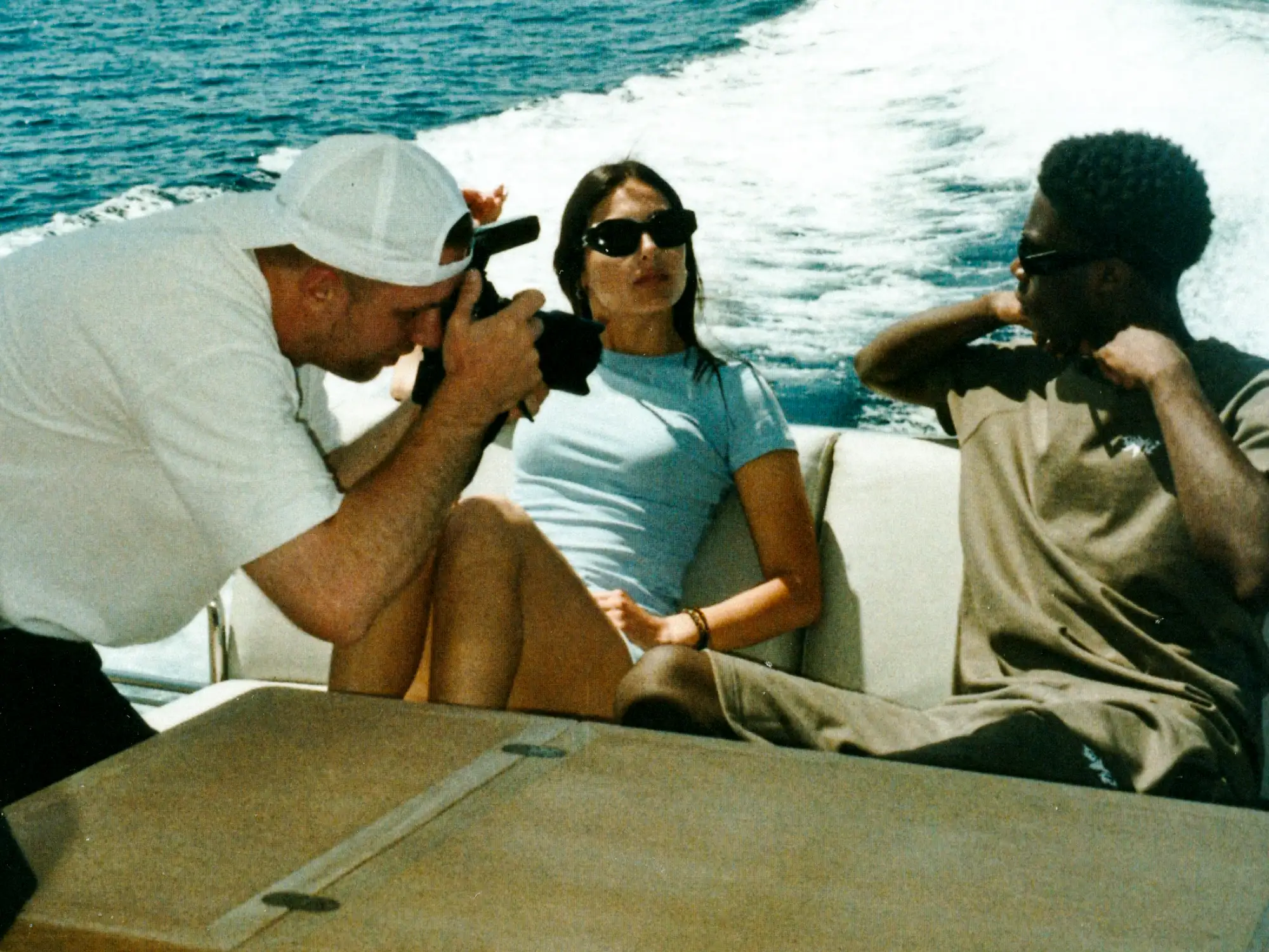 Zwei Personen sitzen am Tisch auf dem Yachtdeck, mit der Heckwelle im Hintergrund.