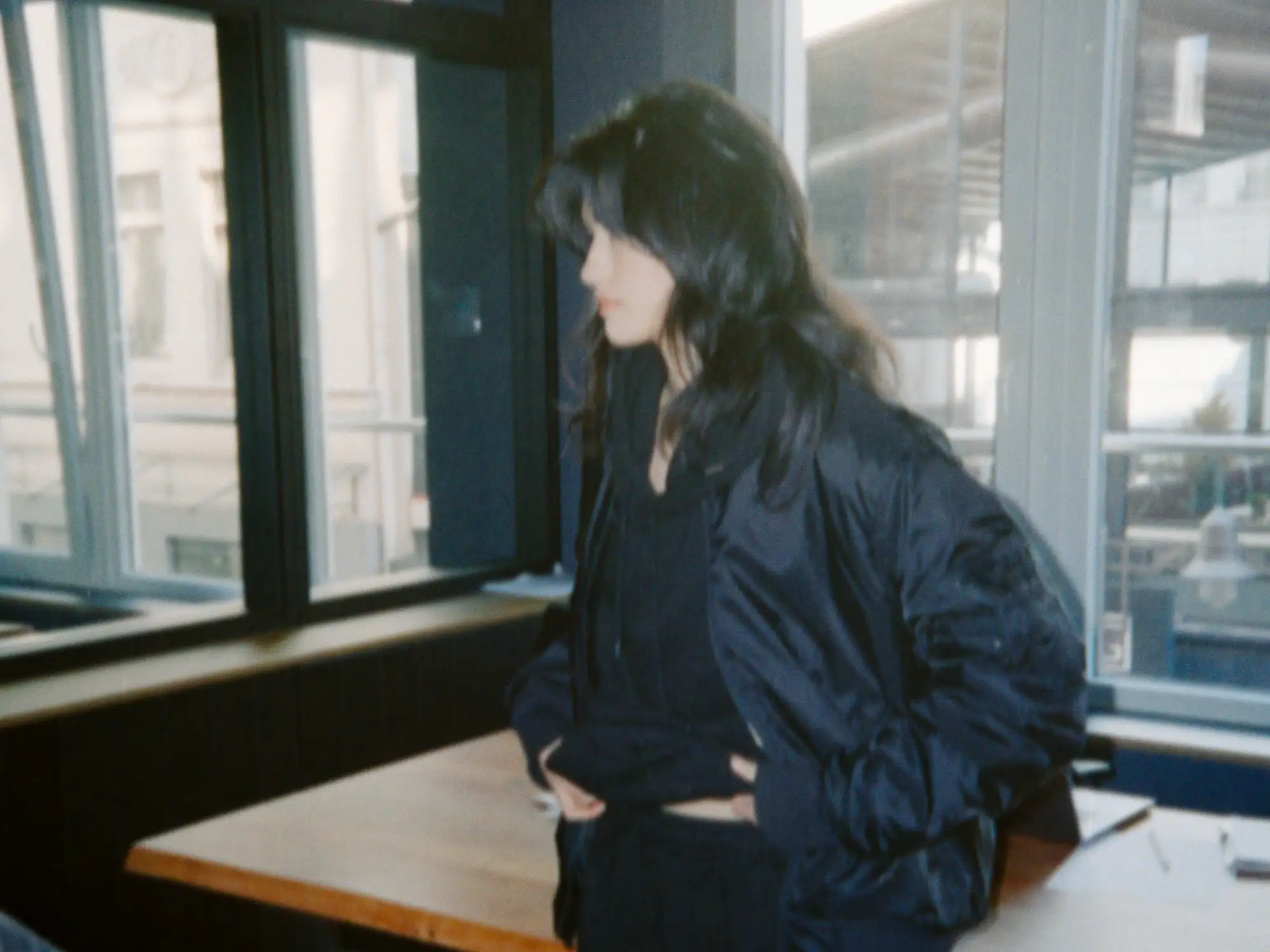 Augustina im schwarzen Outfit am Bürofenster während des African-Sauvage-Shootings in Wuppertal.