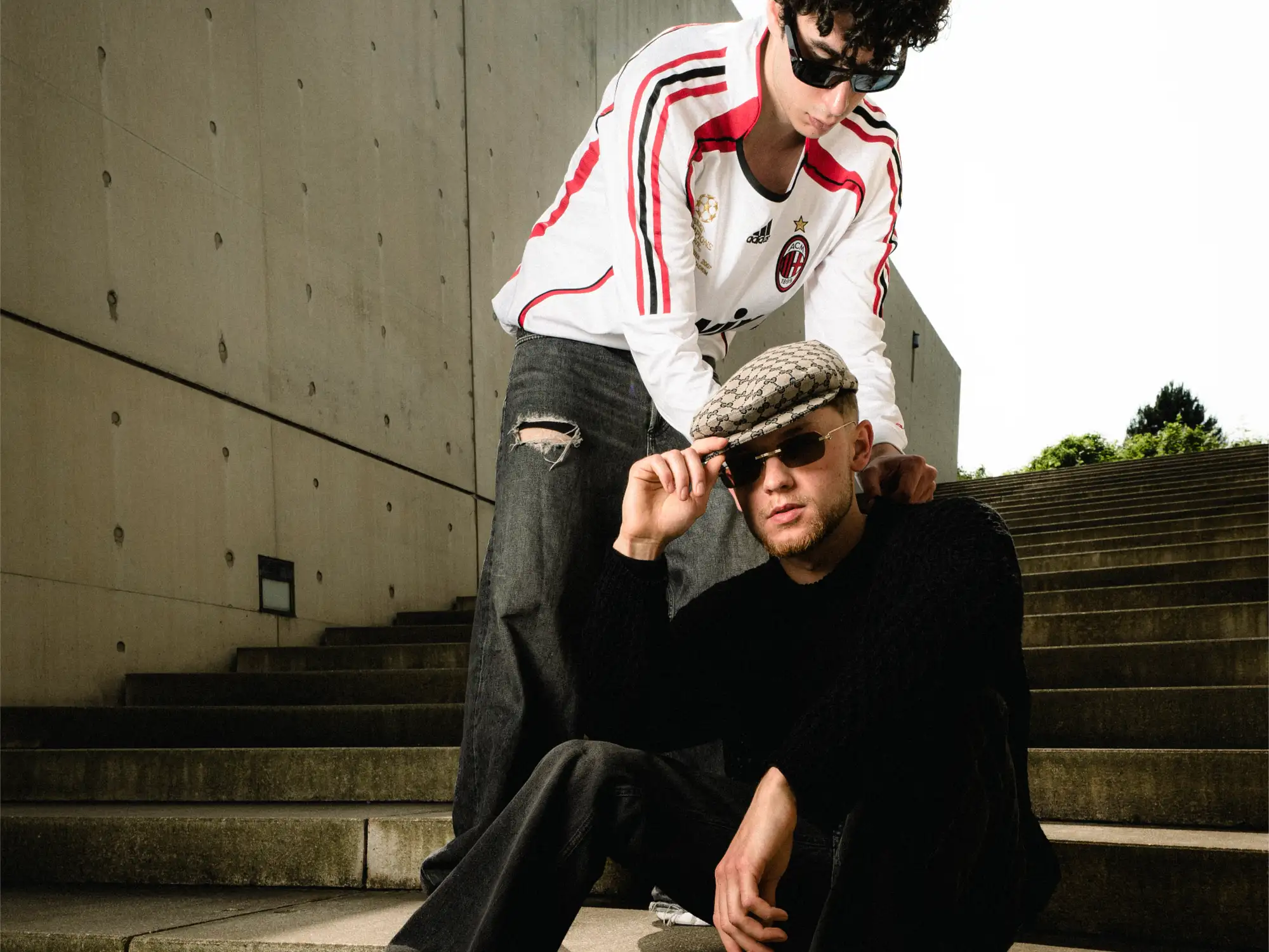 Stylist Casadricci richtet Stroms gemusterte Kappe, während der Musiker auf einer Betontreppe sitzt.