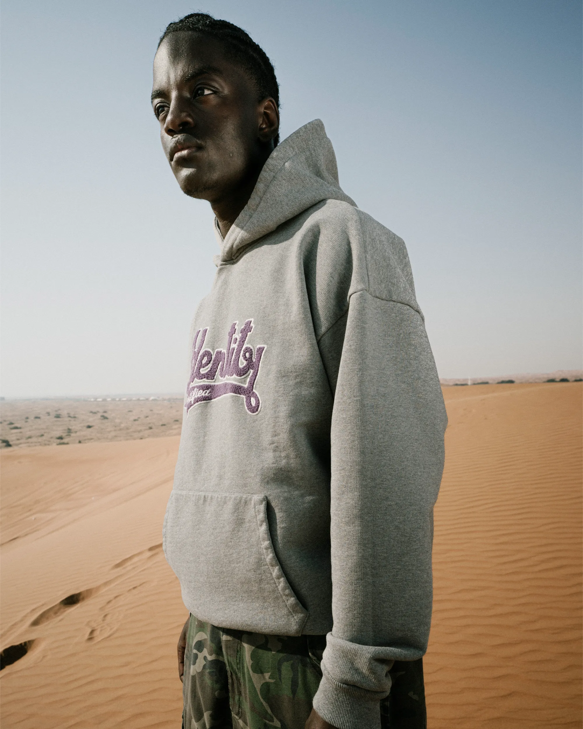Ibo Ouro-Bodi im grauen Hoodie der Certified Identity Signature Collection vor der Wüstenlandschaft.