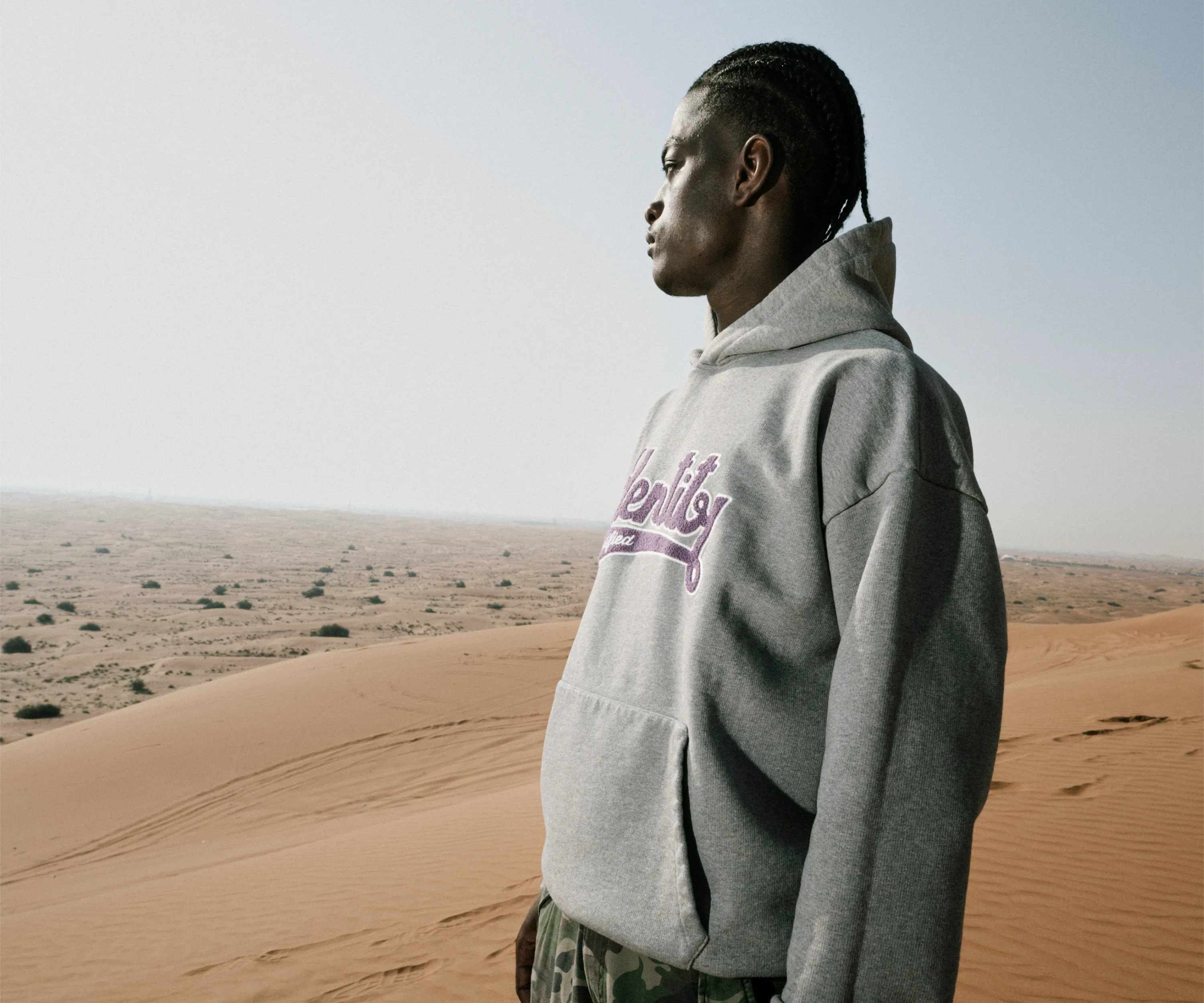 Ibo Ouro-Bodi im grauen Certified-Identity-Hoodie im Profil vor den Sanddünen der Vereinigten Arabischen Emirate.