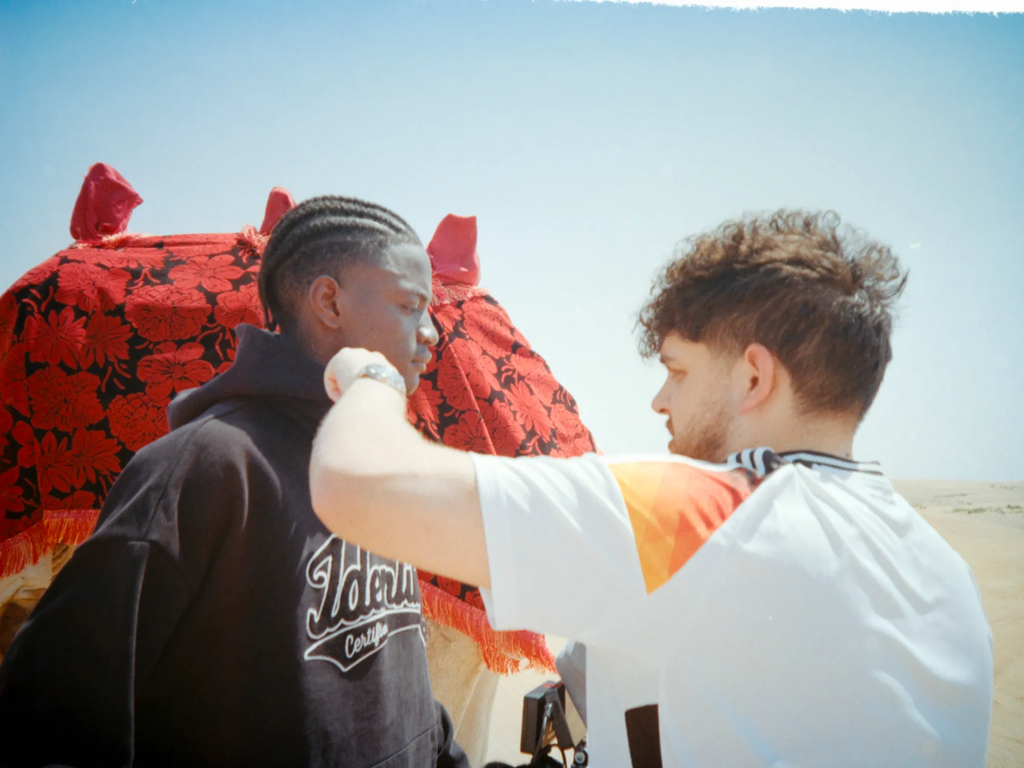 Ein Teammitglied richtet Ibo Ouro-Bodis Styling neben einem Kamel beim Certified-Identity-Shooting.