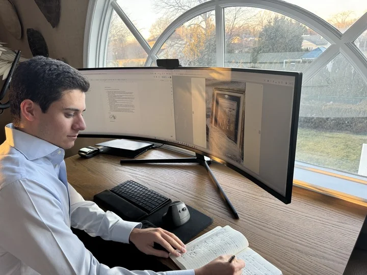 A man appraising furniture in a home. Cartoon image in purple. 