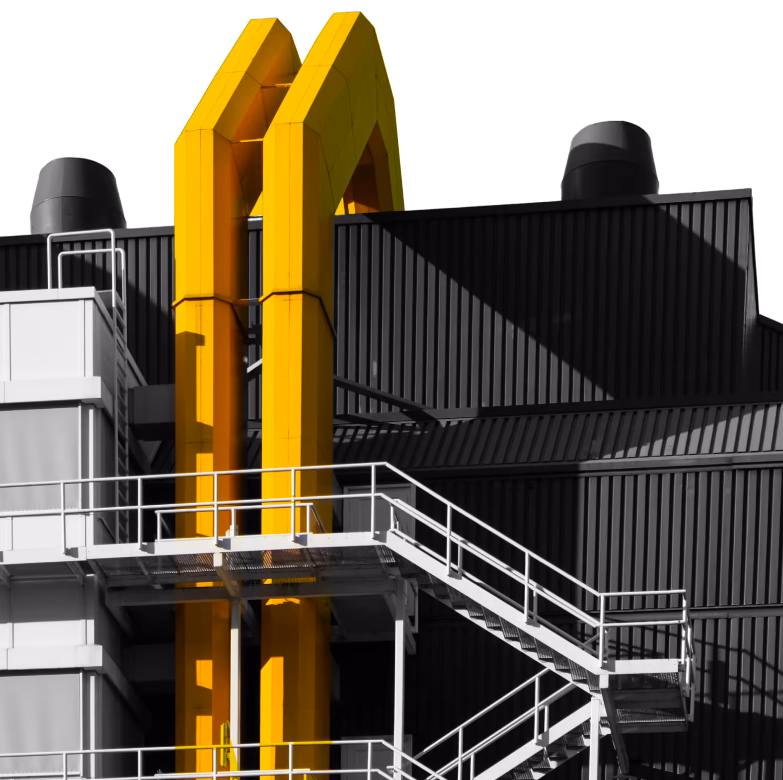 Industribygning med fremtrædende gule ventilationsrør og hvid metaltrappe.