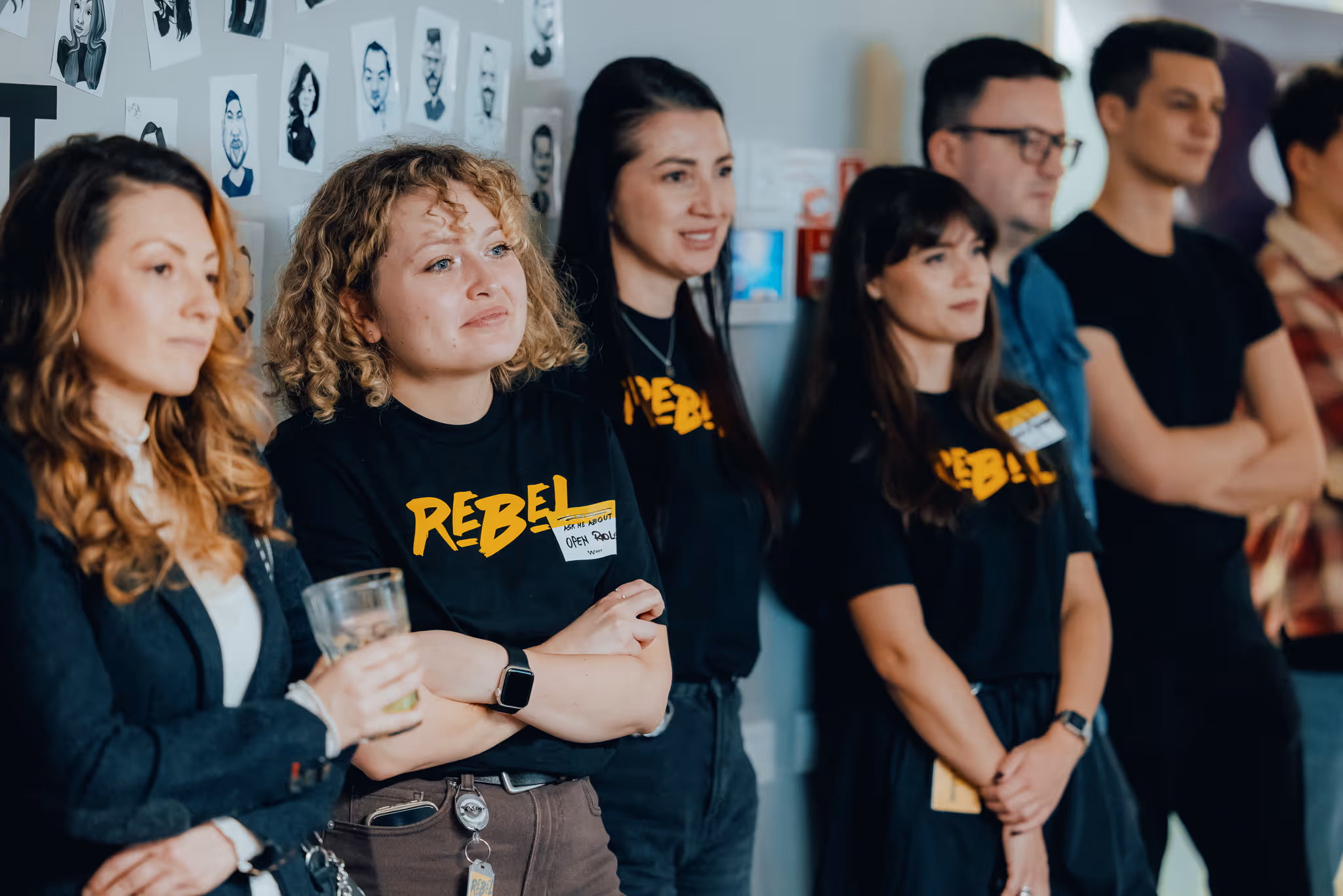 Four young adults gathered around a table, smiling and looking at two laptops during a collaborative work session.